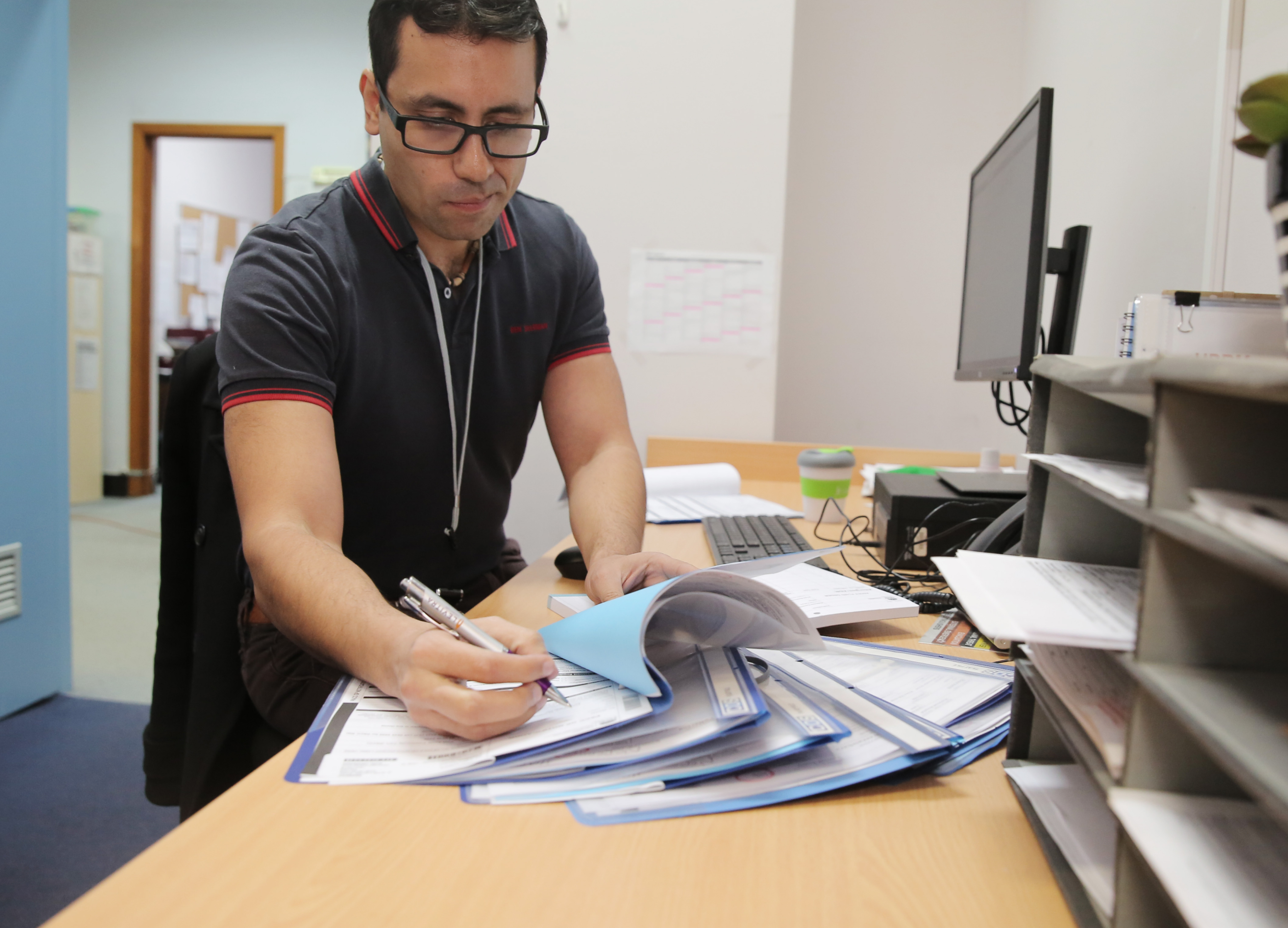 Health worker at a desk completing paperwork and reviewing patient forms. Health worker at a desk completing paperwork and reviewing patient forms.